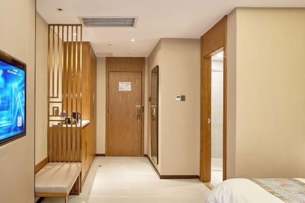 A hotel room with a bed, a TV mounted on the wall, a wooden partition, and a door leading to another room. - Yitel Hotel (Beijing Shilihe Happy Valley Zhoujiazhuang Subway Station) (Beijing)