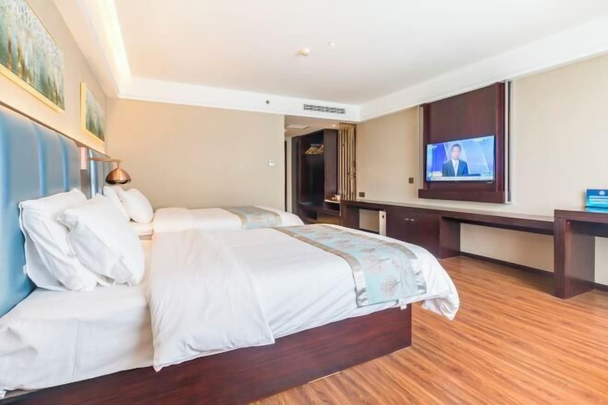 A hotel room with a large bed, a desk, and a television.
