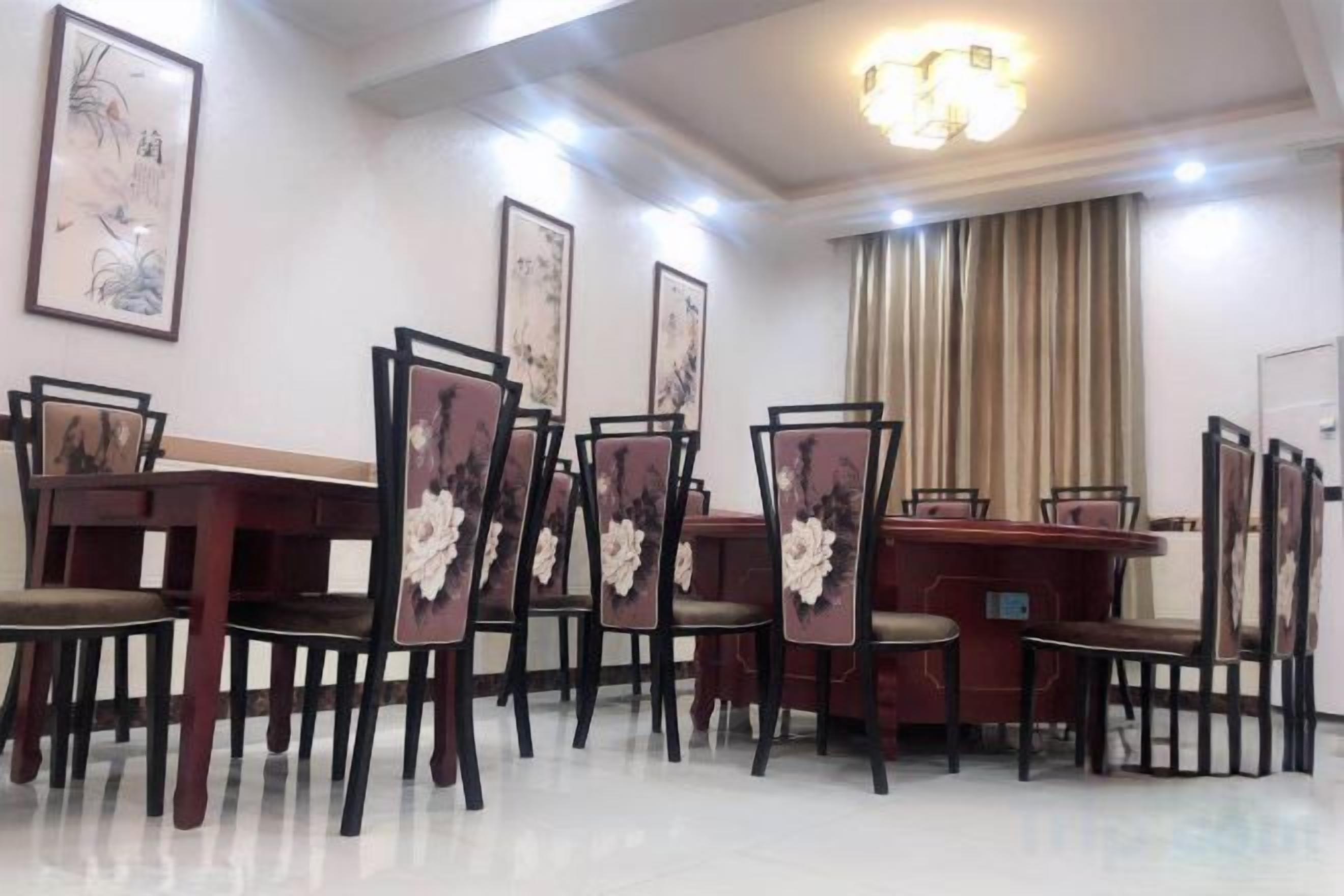 A dining area with a long table and chairs, framed artwork on the walls, and a chandelier.