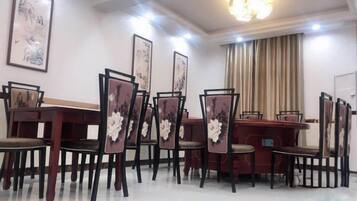 A dining area with a long table and chairs, framed artwork on the walls, and a chandelier.