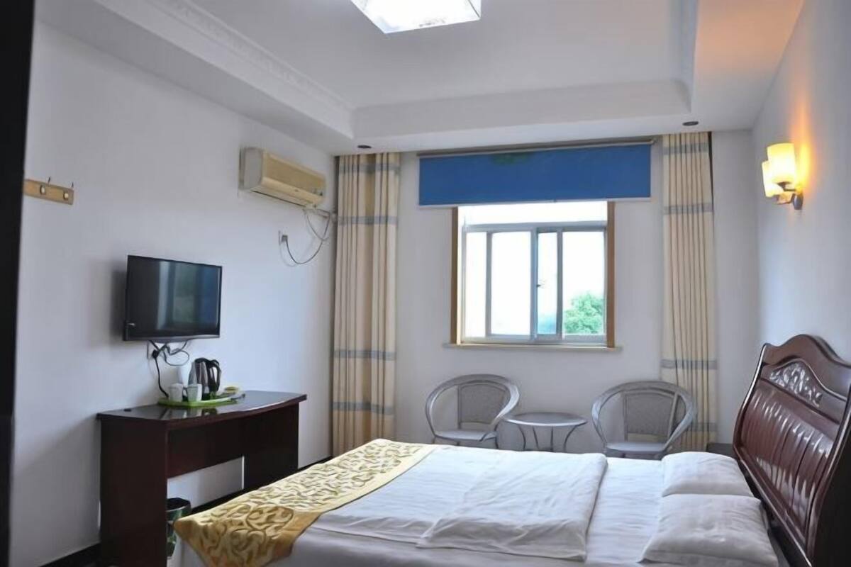 A hotel room with a bed, a TV, a desk, a chair, and a window with curtains.