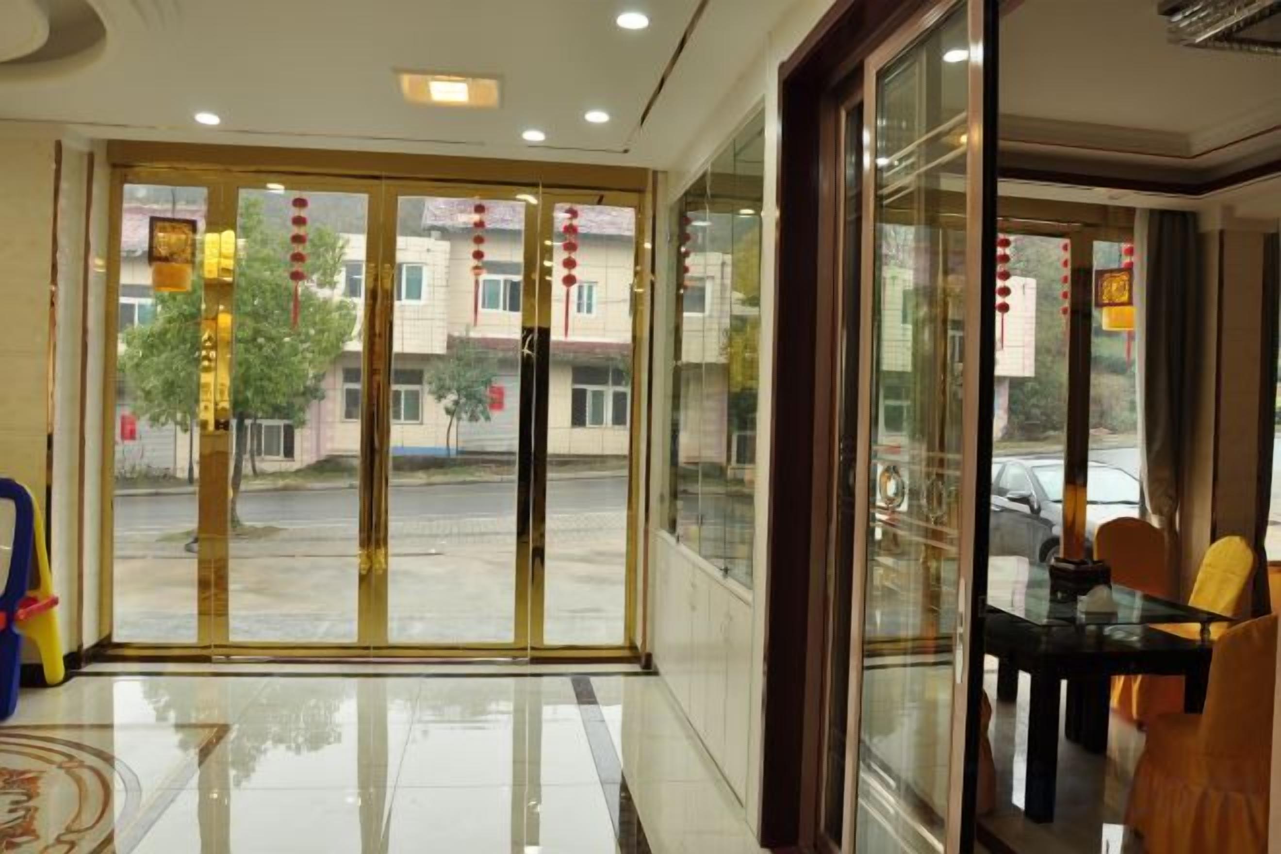 Vestíbulo de hotel con puerta de cristal de entrada, mostrador de recepción y una zona de estar con sillas.
