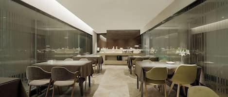 A modern dining area with glass partitions, a central island, and multiple seating arrangements.