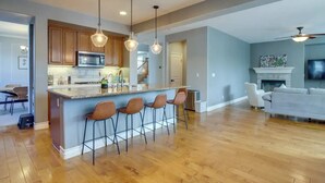 Una cocina amplia con una isla central, taburetes de bar e iluminación colgante.