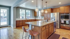 Una cocina moderna con encimeras de granito, electrodomésticos de acero inoxidable y armarios de madera.