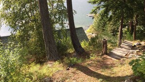 Un área boscosa con una escalera de madera que desciende hacia un muelle a orillas de un lago.