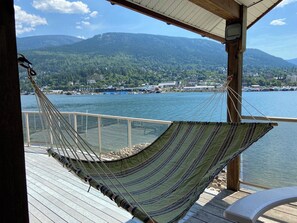 A hammock on a wooden deck overlooking a body of water with a mountainous backdrop. - Cottage on a private sandy beach with a gorgeous view of the city of Nelson.  (Nelson)