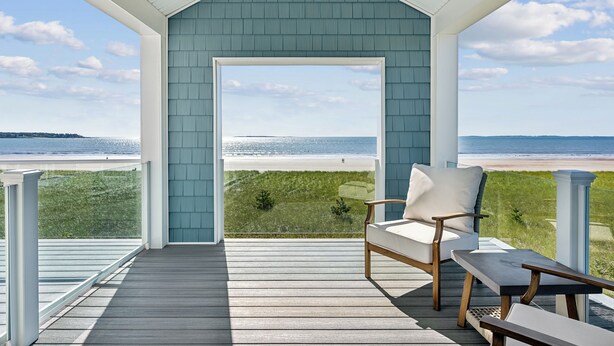 Une terrasse couverte avec vue sur la plage, une chaise et un banc.