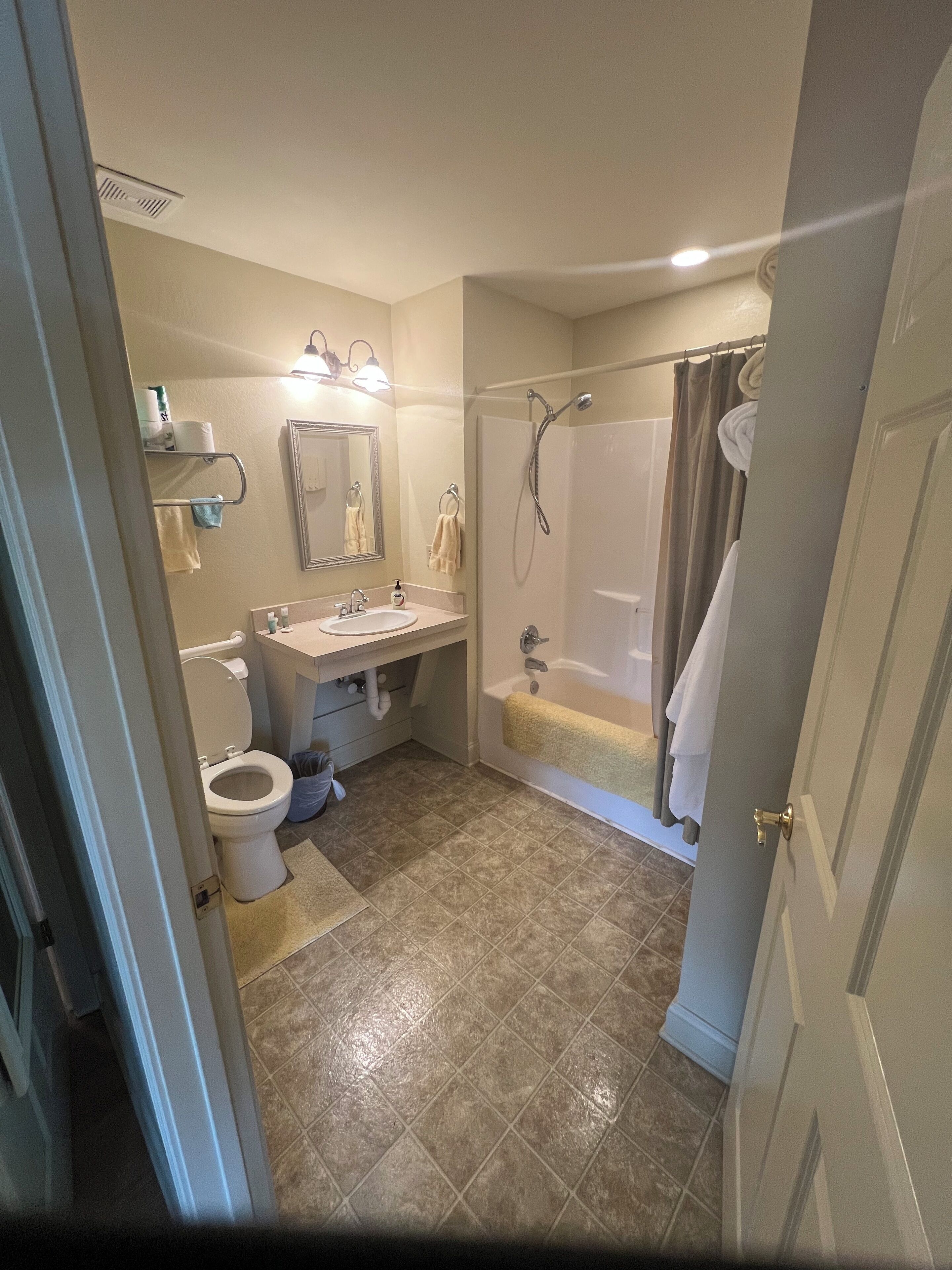 Une salle de bain comprenant des toilettes, un lavabo, un miroir, une douche et une baignoire.