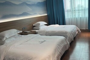 A hotel room with two beds, a wooden headboard, a nightstand with a phone, and a mountain view mural. - Yuanle Hotel (Boluo)