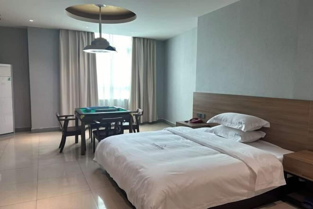 Una habitación de hotel con cama, escritorio y silla, una mesa y una lámpara colgante.