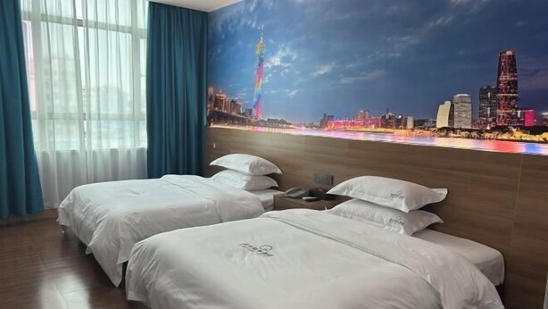 A hotel room with two beds, a cityscape mural, a wooden floor, and a window with curtains. - Yuanle Hotel (Boluo)