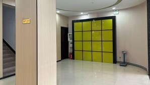 A modern hotel lobby with a bright yellow door, a staircase, and a clean, tiled floor. - Yuanle Hotel (Boluo)