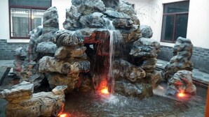 A rock waterfall feature with water cascading down, surrounded by large rocks. - Shanghecheng Hotel (Feixi)