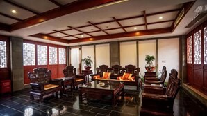 A traditional-style room with wooden furniture, a tiled floor, and a ceiling with a grid pattern. - Shanghecheng Hotel (Feixi)