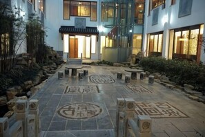 A courtyard with stone benches, a central pathway, and traditional Chinese patterns on the floor. - Shanghecheng Hotel (Feixi)