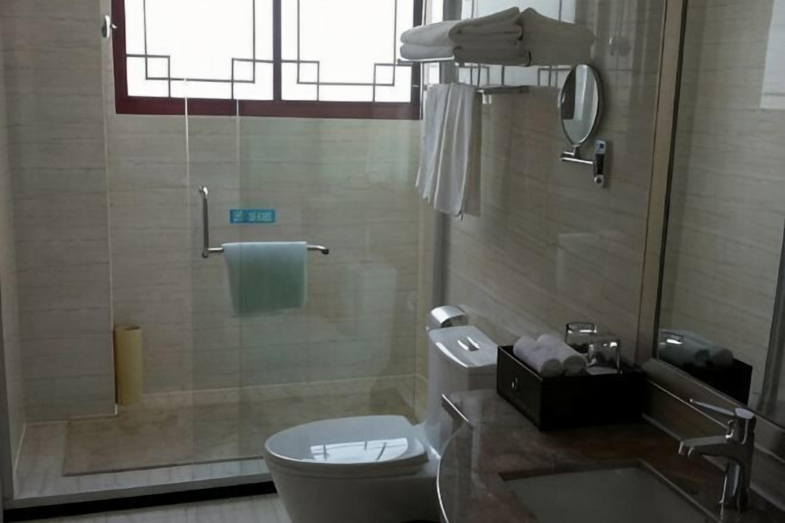 Un baño moderno con cabina de ducha de vidrio, inodoro, lavabo y espejo.