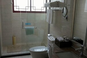 Un baño moderno con cabina de ducha de vidrio, inodoro, lavabo y espejo.
