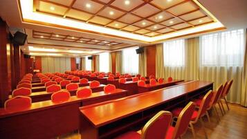 A conference room with rows of red chairs and a long table, equipped with a ceiling light fixture.