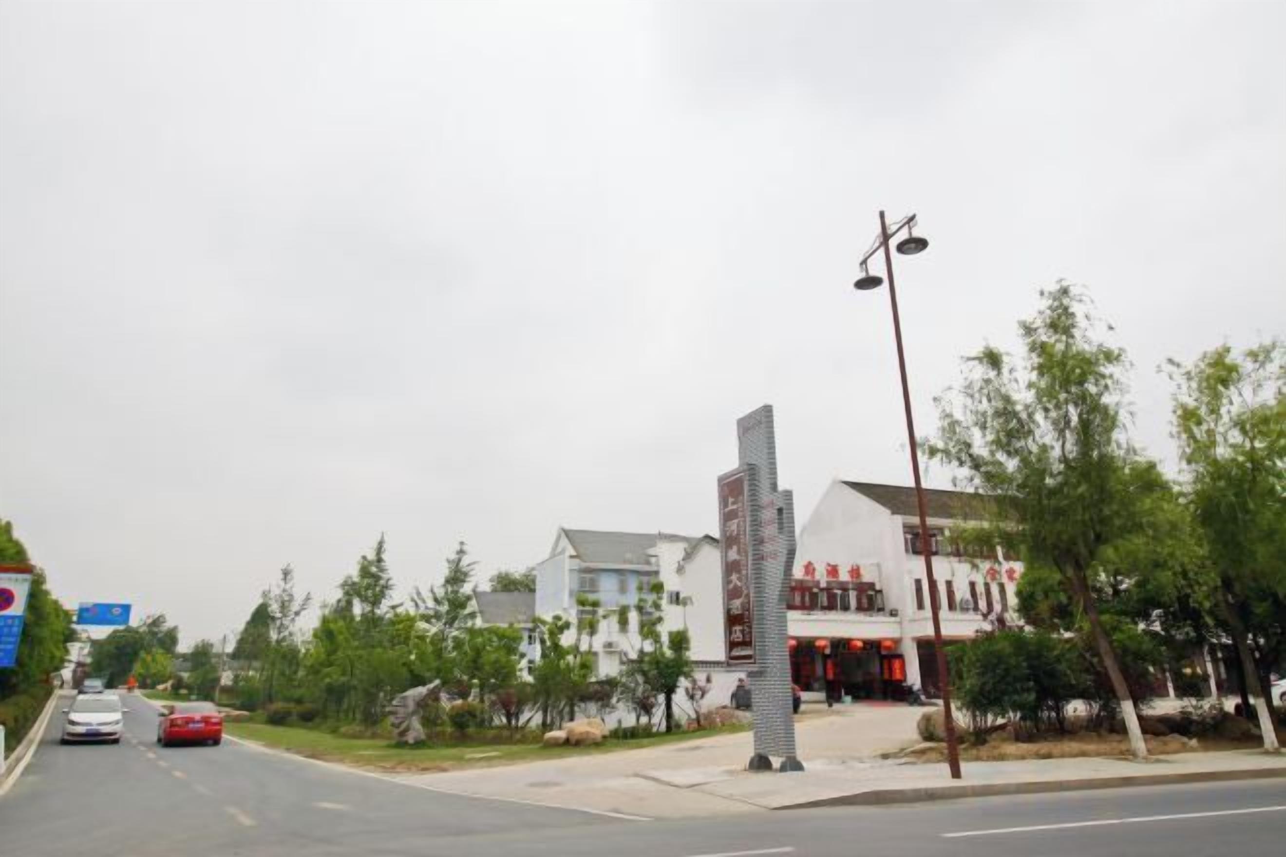 A street view with a building that has a modern design, a clear sky, and a few cars on the road.