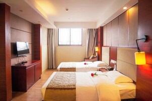 Habitación de hotel con dos camas, televisión, escritorio y ventana con cortinas.