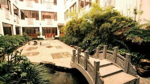 A courtyard with a bridge, potted plants, and a small water feature. - Shanghecheng Hotel (Feixi)