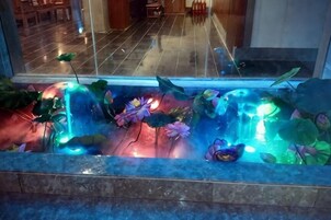 Uma fonte de água decorativa em ambiente interno, com plantas e luzes.