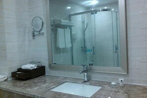 A bathroom with a large mirror, a sink, a shower, and a towel rack.