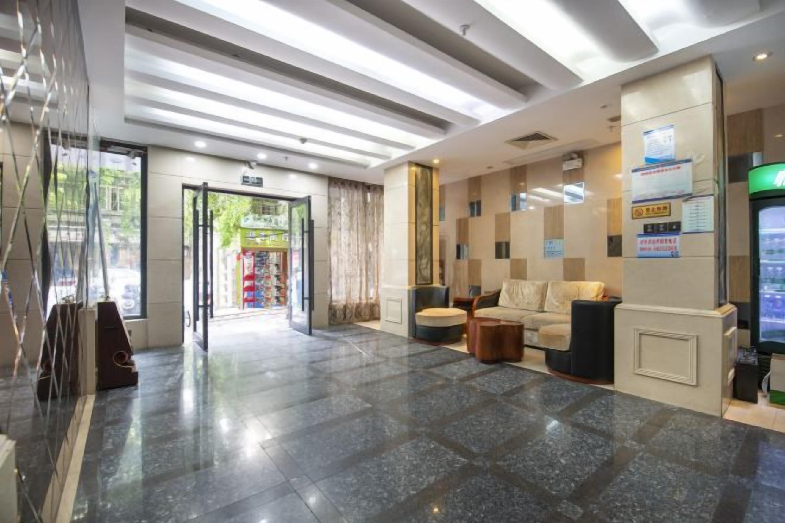 A hotel lobby with a reception desk, seating area, and a glass door entrance.