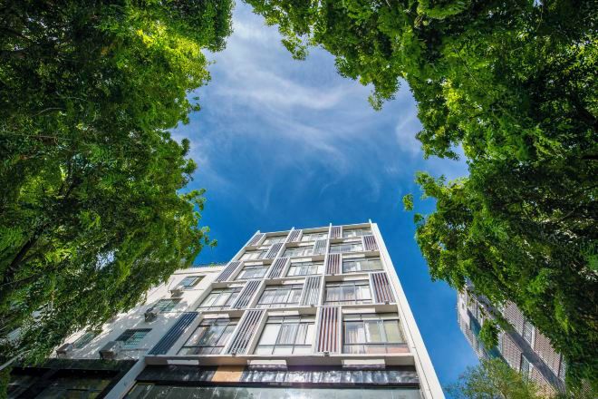 A high-rise building with a grid-like facade, surrounded by trees.