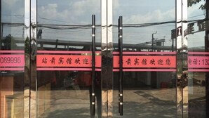 A glass door with a reflection of a building and a sign with Chinese characters. - Fuyang Station Front Hotel (Yiyang)