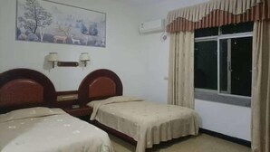 A room with two beds, a painting on the wall, an air conditioning unit, and a window with curtains. - Fuyang Station Front Hotel (Yiyang)