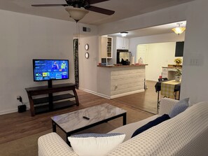 A living room with a TV, sofa, coffee table, and a dining area with a table and chairs. - Nice private house near downtown Raleigh with WiFi, AC, heat (Raleigh)
