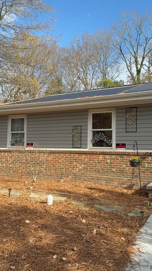 A residential house with a brick foundation, a grey siding exterior, and a front yard with mulch and a stone pathway. - Nice private house near downtown Raleigh with WiFi, AC, heat (Raleigh)