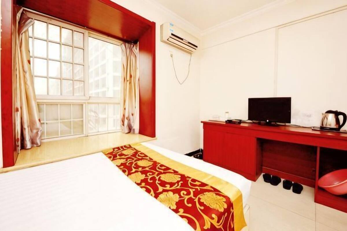 Een hotelkamer met een bed, een bureau met een televisie en een rode garderobe.