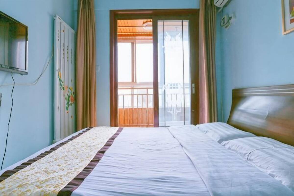 Een slaapkamer met een bed, een raam, gordijnen en een radiator.