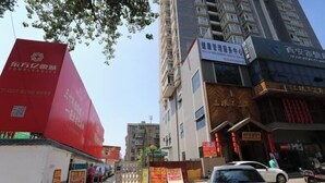 A street view with a red building on the left, a multi-story building with a sign for a health management service center, and a storefront with red lanterns. - Sunshine Hotel Xijing Hospital (Xi'an)