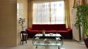 Ένα σαλόνι με έναν κόκκινο καναπέ, ένα τραπεζάκι σαλονιού από γυαλί και ένα φυτό σε γλάστρα.