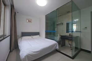 A hotel room with a bed, a glass-enclosed bathroom, and a window with curtains. - Yongchang Hotel (Ningbo)