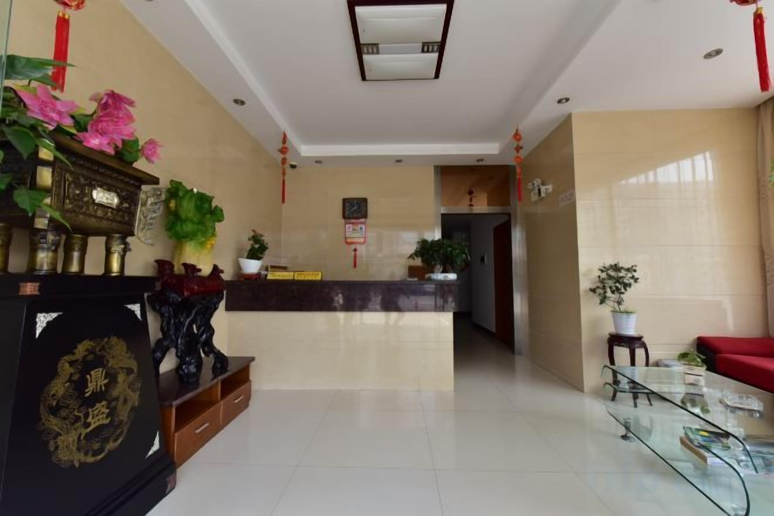 A hotel reception area with a reception desk, a potted plant, and a decorative display.