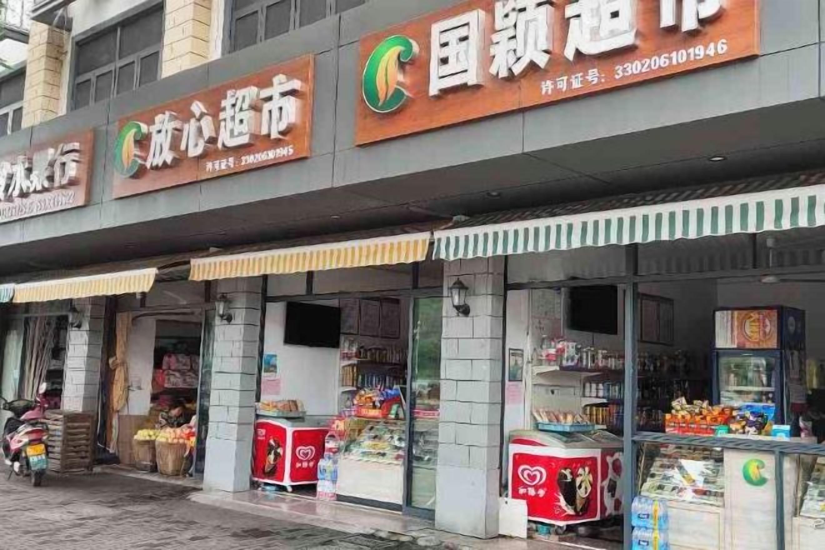 A storefront with multiple signs, including one for a store named '国领超市' and another for 'C.心超市'. There are refrigerated display cases and a motorcycle parked outside.