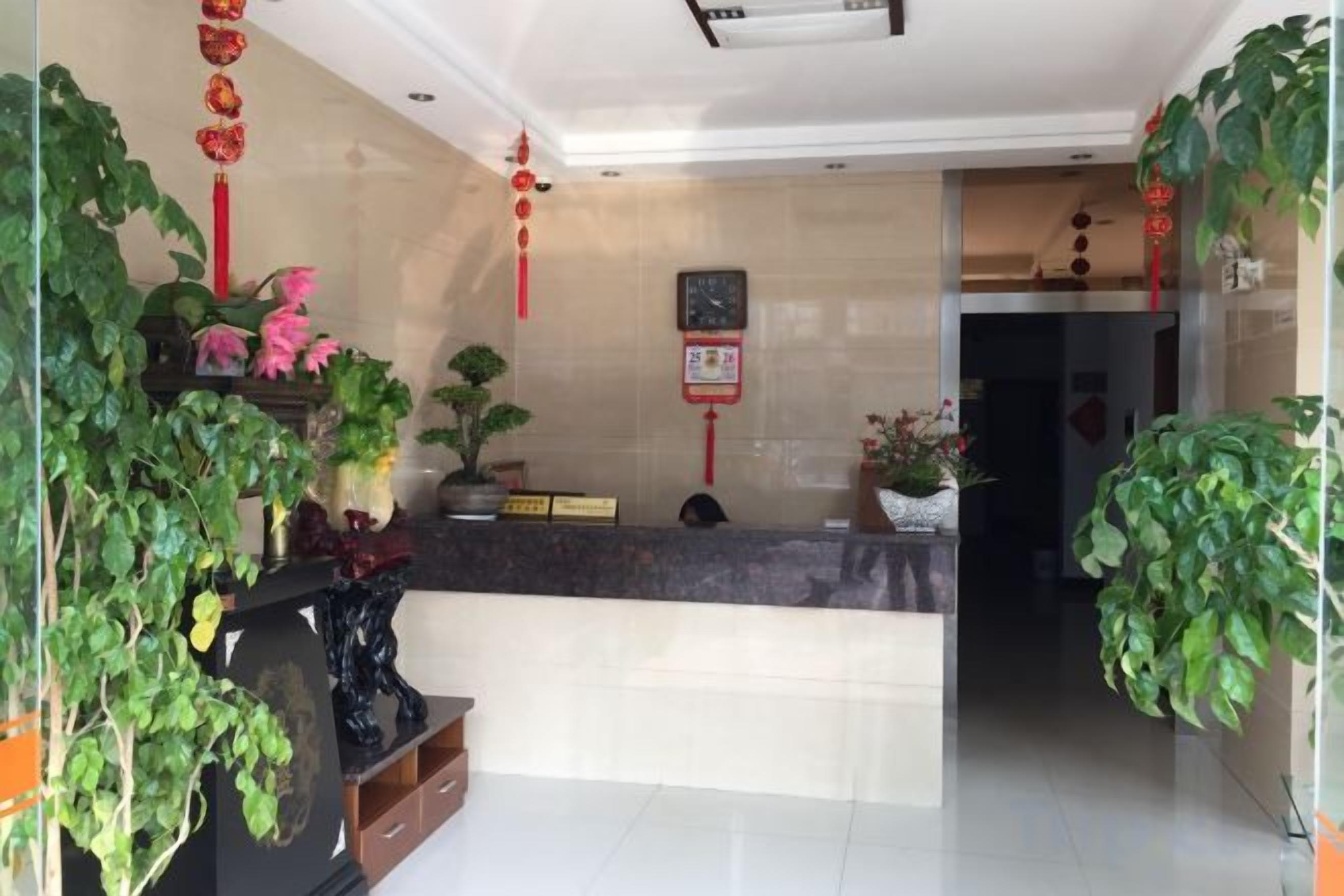 A reception area with a counter, potted plants, and a wall clock.