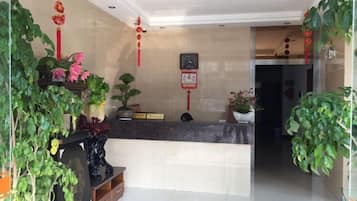 A reception area with a counter, potted plants, and a wall clock.