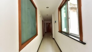 Ένας διάδρομος με πλακάκια στο δάπεδο, ξύλινα διακοσμητικά στοιχεία και μεγάλα παράθυρα και στις δύο πλευρές.