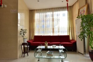 A living room with a red sofa, a glass coffee table, and a potted plant. - Yongchang Hotel (Ningbo)