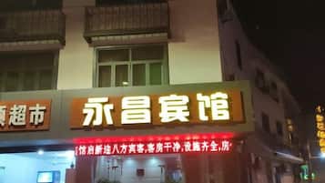 Un hotel con un letrero llamativo y un anuncio de neón que indica los servicios.