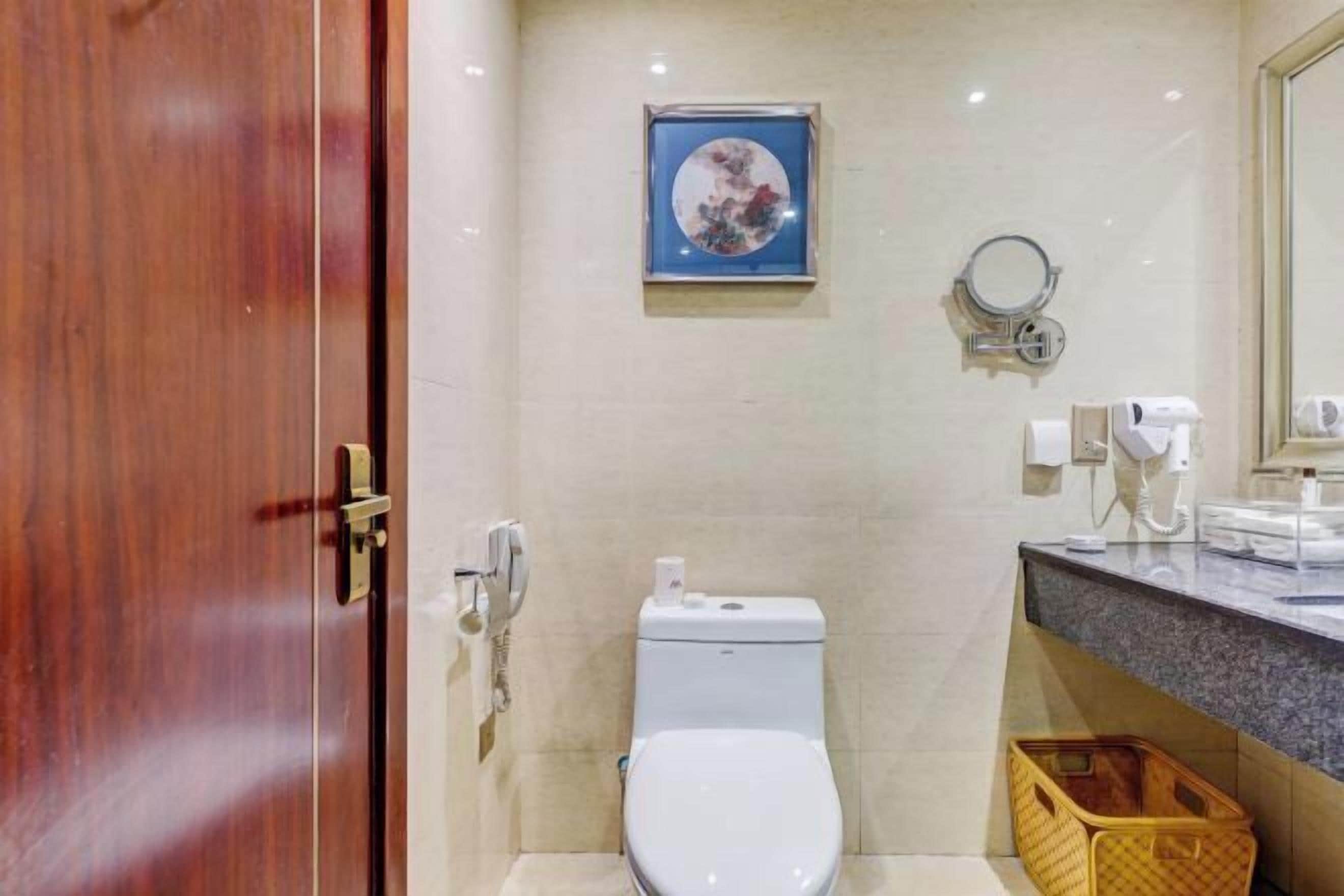 Ein modernes Badezimmer mit Toilette, Waschbecken mit Spiegel und einem gerahmten Bild an der Wand.