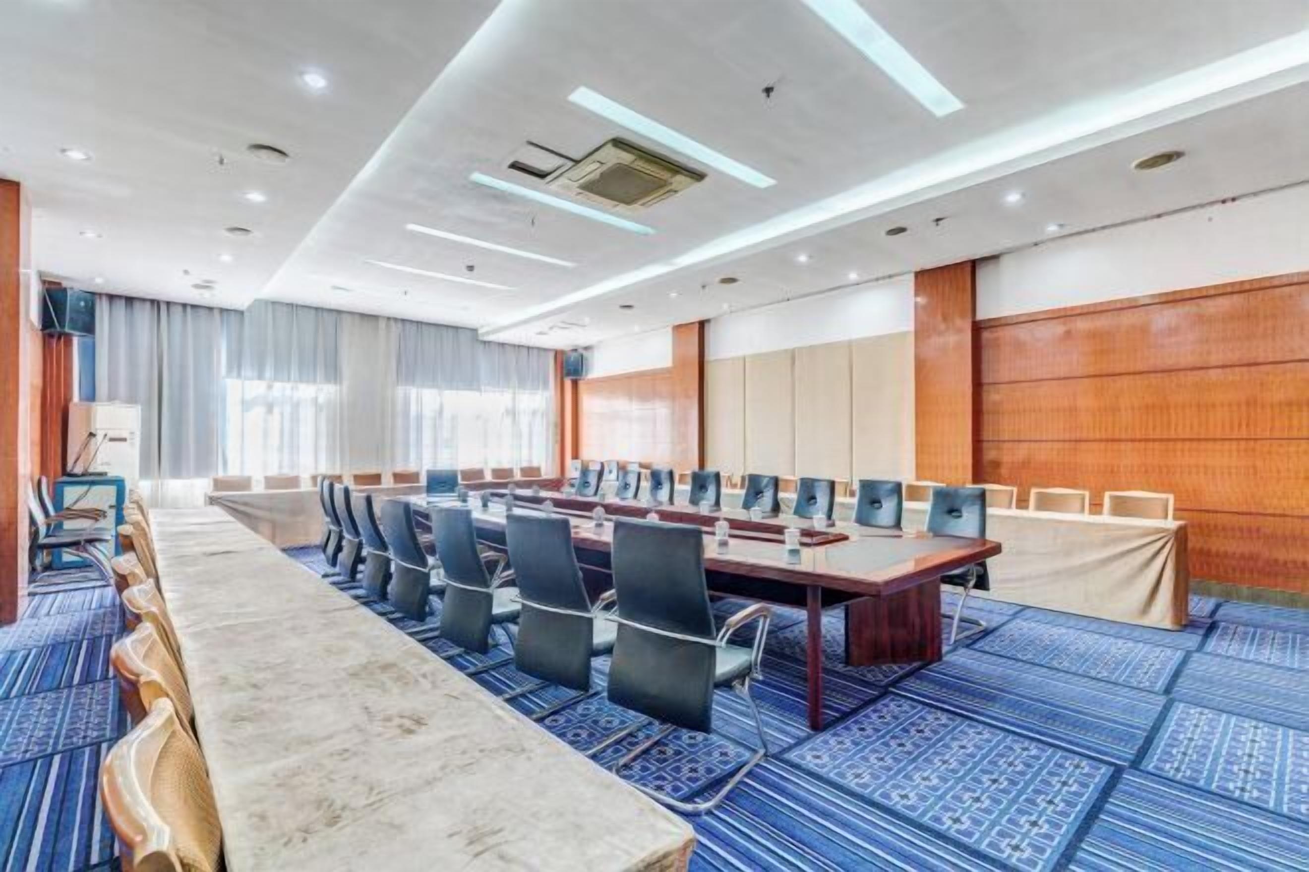 A conference room with a long table, chairs, and a carpeted floor.