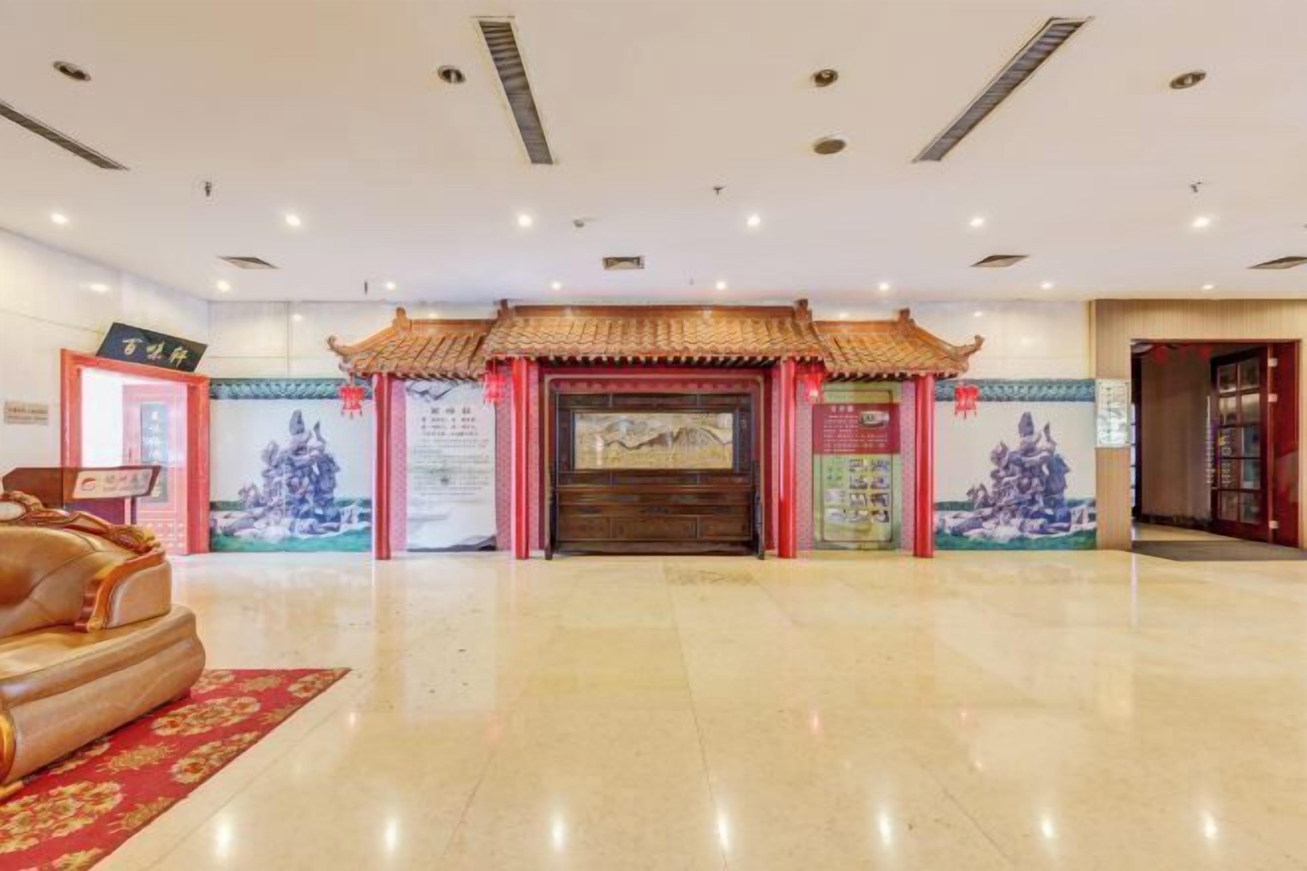 A lobby with a traditional Chinese architectural entrance, a reception desk, and a massage chair.