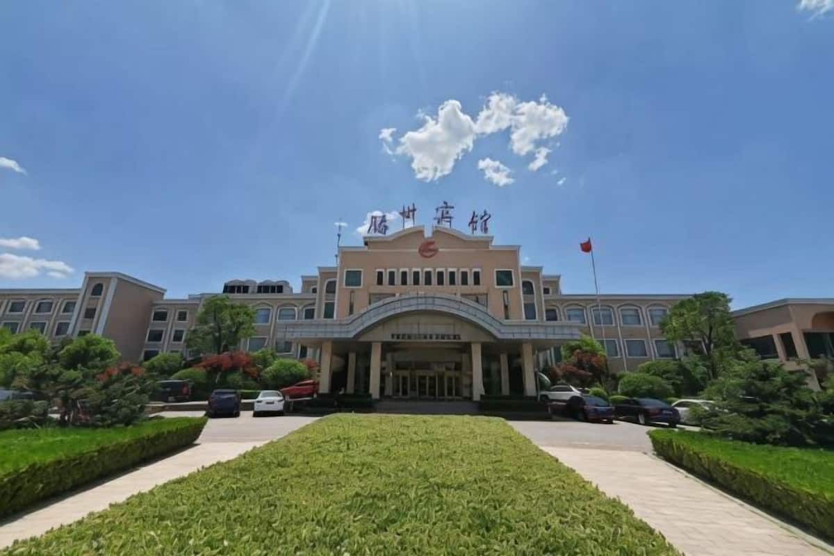 A large building with a prominent entrance, a flag, and a well-maintained lawn.